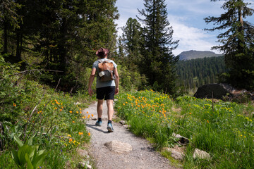 Young traveler with backpack in hat walks along forest path. Travel summer concept with vintage style hipster travel