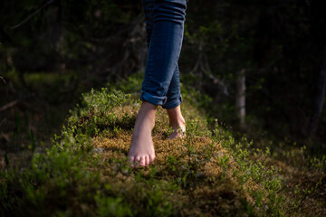 Close-up of bare feet on moss in forest