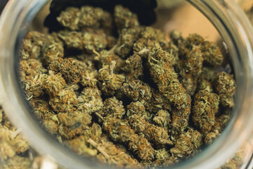 Modern alternative medicine concept. CBD CBG marijuana weed tops in a glass jar. Closeup shot. High...