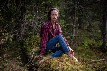 Attractive young girl in hipster clothes inforest on moss posing