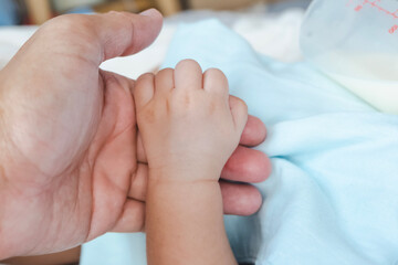 baby holding hands father