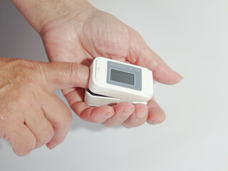 Woman using modern fingertip pulse oximeter on light background, closeup. Woman Uses Pulse Oximeter