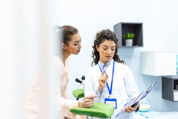 Gynecologist talking with young female patient during medical consultation in modern clinic. Patient with a gynecologist during the consultation in the gynecological office - obrazy, fototapety, plakaty