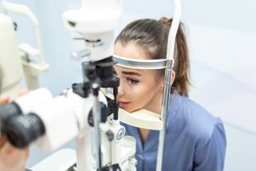 Eye doctor with female patient during an examination in modern clinic. Ophthalmologist is using special medical equipment for eye health
