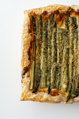Baked puff pastry pie with cheese and asparagus on a white background, top view, copy space
