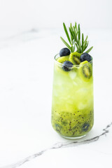 Refreshing drink with kiwi smoothie, summer sweet fruit juice with blueberries and rosemary