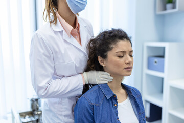 Obraz premium Endocrinologist examining throat of young woman in clinic. Women with thyroid gland test . Endocrinology, hormones and treatment. Inflammation of the sore throat