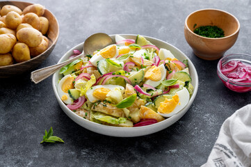 Potato salad with eggs, cucumbers and red pickled onions. Delicious healthy summer salad. Dark background.