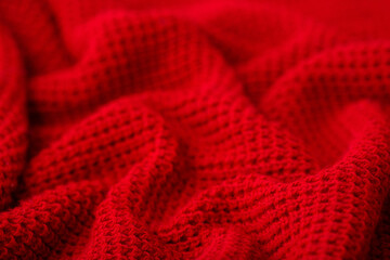 Knitted surface of woolen things as a background. Close-up of soft fabric red color knitted patterns texture. Warm winter clothing. Background textile surface with copy space for text.