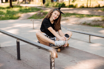 Stylish teenager girl with skateboard sitting and chilling in the skaters park