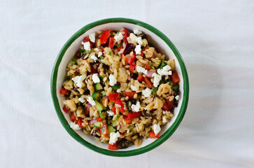Multi-colored Orzo salad on the table. Tomatoes, cucumbers, feta cheese, olives, red onions, sweet...
