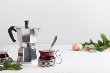 Cups of fresh coffee and coffee maker on white table