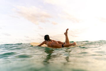 Asian woman surfer paddling surfboard and riding the wave in the sea at tropical beach at summer sunset. Healthy female enjoy outdoor activity lifestyle water sport exercise surfing on travel vacation - Powered by Adobe
