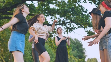Girls are dancing outside the city on a picnic.