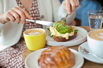 Avocado toast closeup. Young woman at brunch eating and drinking coffee and avocado toast, millennial lifestyle with food. hipster cafe and restaurant. woman at brunch on Sunday.