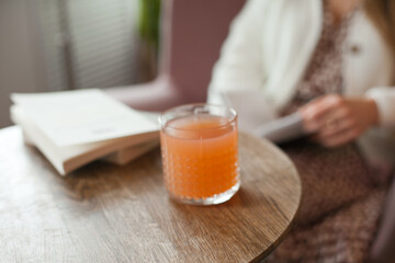 Cocktail or peach juice on the wooden table at cafe near the books. Student lifestyle, reading and studying. Woman spending time at cafe, having lunch or breakfast.