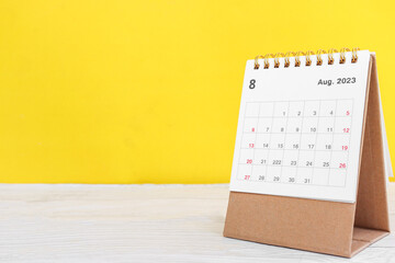 August calendar 2023 on wooden table on yellow background - obrazy, fototapety, plakaty