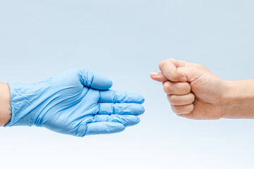 Hand shows a fig sign to a hand in blue glove: doctor or nurse. Corruption