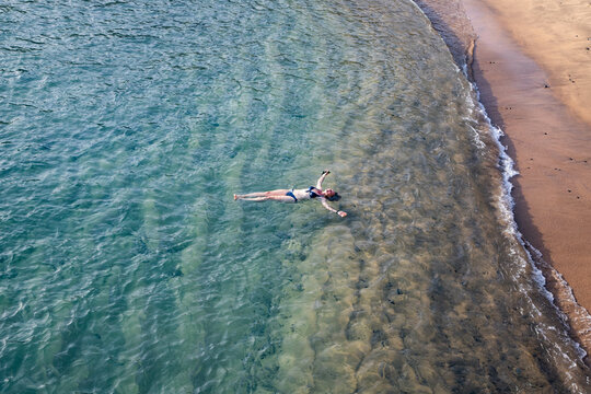 top view of woman floating in the sea near sandy beach