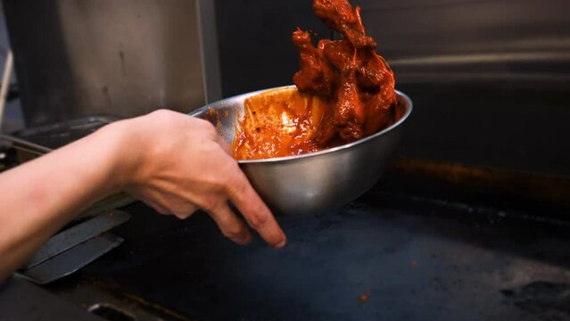 Chef tosses fried chicken wings in vibrant orange buffalo sauce, slow motion 4K