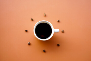 Black coffee cup on brown background with Coffee beans arrange as forming clock face