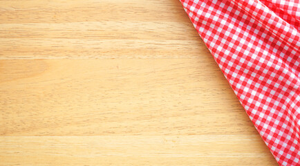 Wood table background with crumple pink plaid fabric or tablecloth in the right corner 