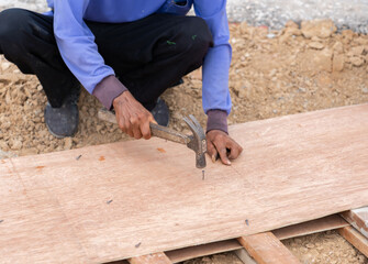 Worker use hammer hit nails on formwork.