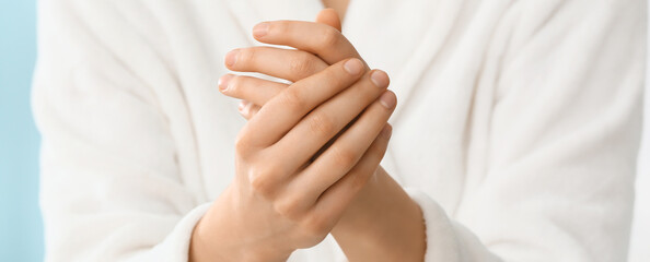 Young woman applying cosmetic cream onto her hands, closeup