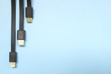 Smartphone or mobile phone standard charging cable plugs flat lay. Micro USB, type c and lightning cable in blue background with copy space.