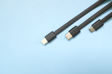 Smartphone or mobile phone standard charging cable plugs flat lay. Micro USB, type c and lightning cable in blue background with copy space.
