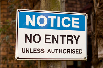 Notice. No entry unless authorised sign on a wooden pole