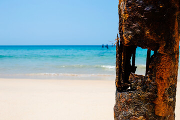 Rusty steel pillar over blurred beach background, environmental concept background, summer outdoor day light