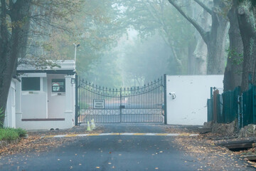 high security entrance to an estate driveway with closed metal gates and police guardhouse concept safety and security - obrazy, fototapety, plakaty