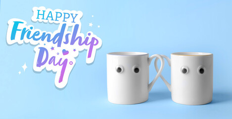 Funny cups and text HAPPY FRIENDSHIP DAY on light blue background