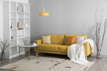 Interior of light living room with yellow sofa, table and shelving unit