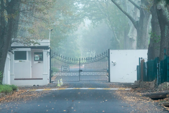 high security entrance to an estate driveway with closed metal gates and police guardhouse concept safety and security