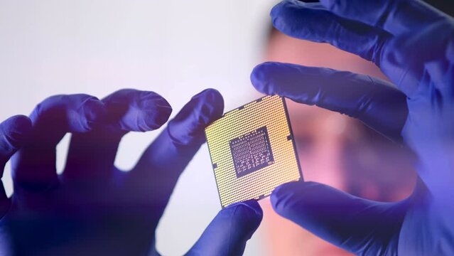 The concept of computer technology: An engineer in a sterile jumpsuit holds a computer microchip in his gloves and examines it. The concept of artificial intelligence