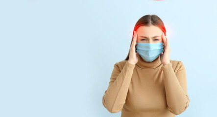 Woman in protective mask suffering from headache on light blue background