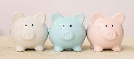 Piggy banks on table against light background