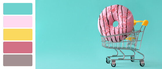 Shopping cart with sweet tasty donut on turquoise background. Different color patterns