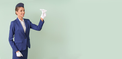 Beautiful stewardess with paper airplane on color background with space for text