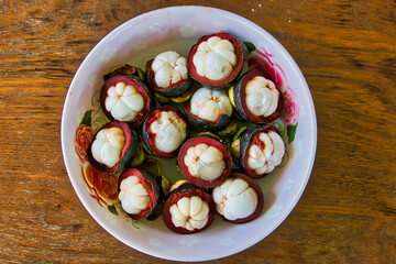 Tropical mangosteen fruits and cross section of purple skin and white seeds on a plate