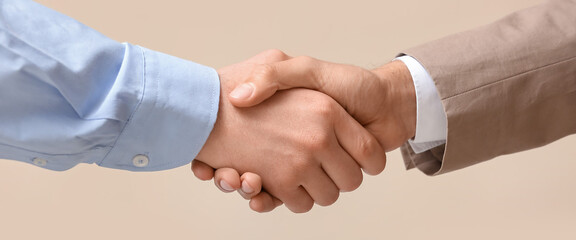 Businessmen shaking hands on beige background