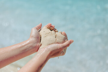woman holding sand making heart shape sea beach on background