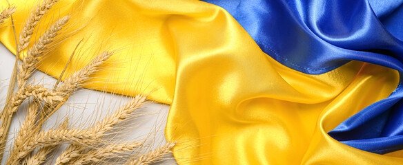 Wheat spikelets and Ukrainian flag on light background, closeup