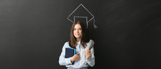 Teenage girl with savings for education near drawn graduation hat on blackboard