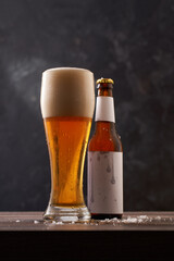 Bottle and glass of beer on black background.