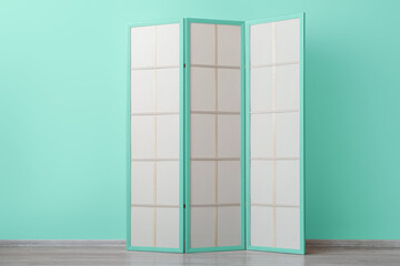 Stylish folding screen near mint wall in room
