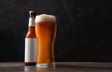 Bottle and glass of beer on black background.