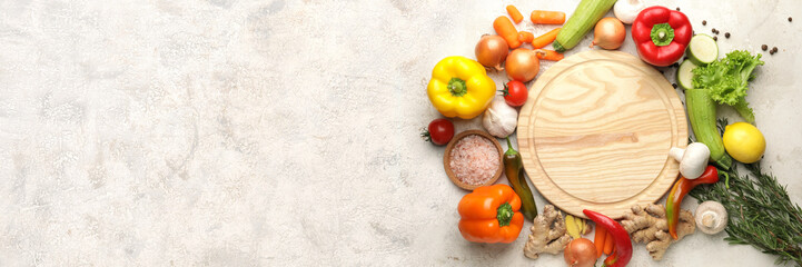 Empty cutting board with fresh vegetables on light background with space for text